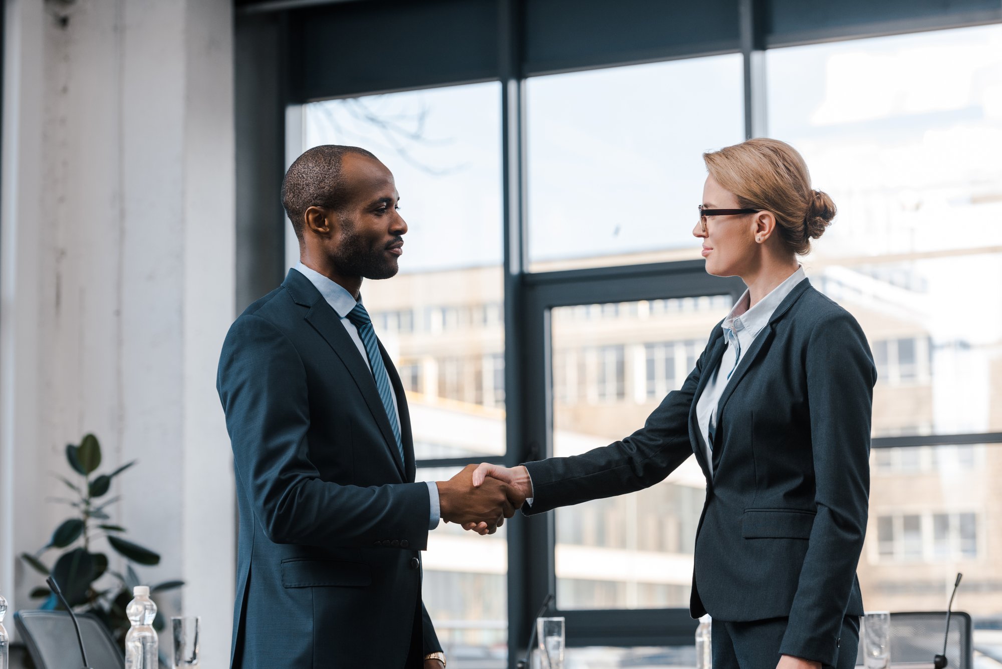 Side view of attractive businesswoman shaking hands with african american businessman