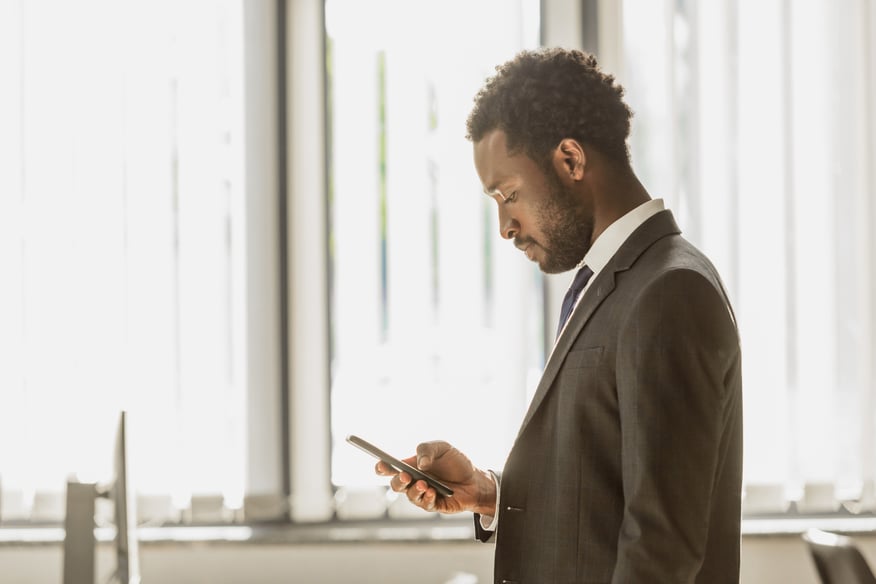 Thoughtful african american businessman using smartphone in office